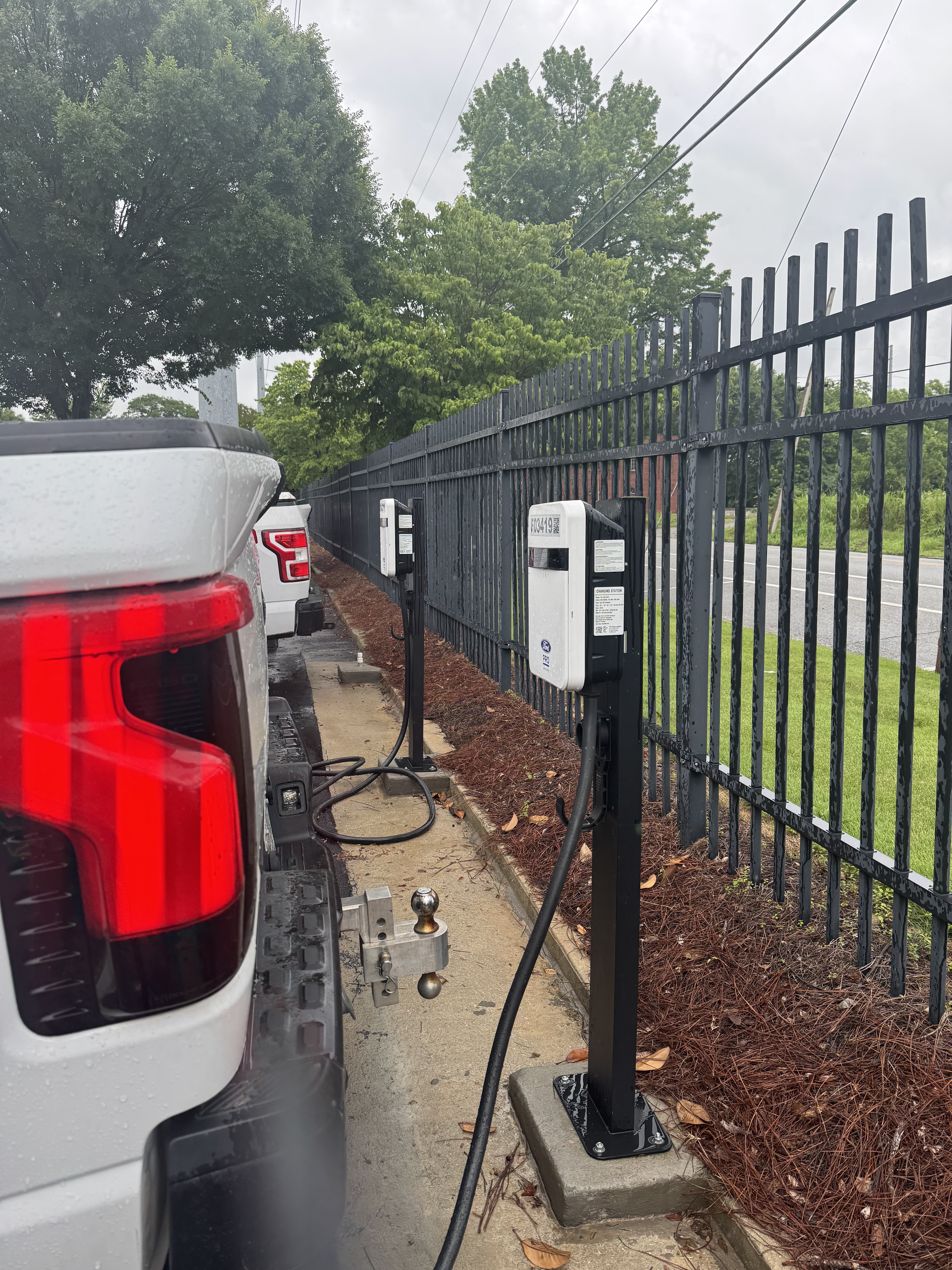 The back of a white truck is shown backed up to a Ford Pro charging station